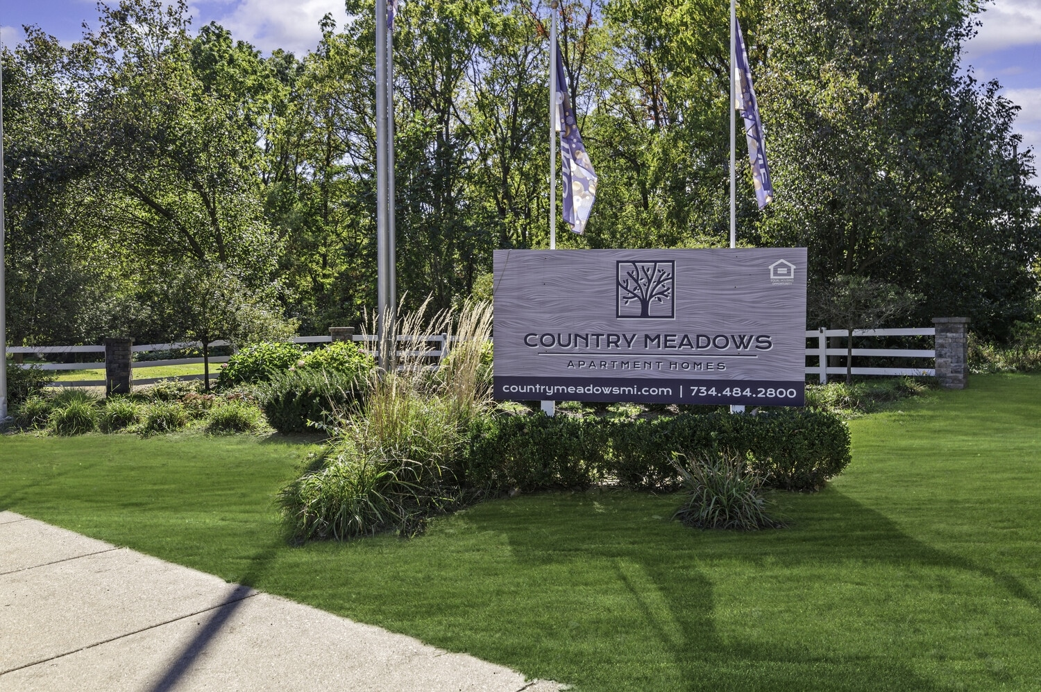Sign for Country Meadows Apartment Homes surrounded by greenery.